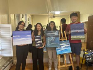 A group of people holding up their paintings